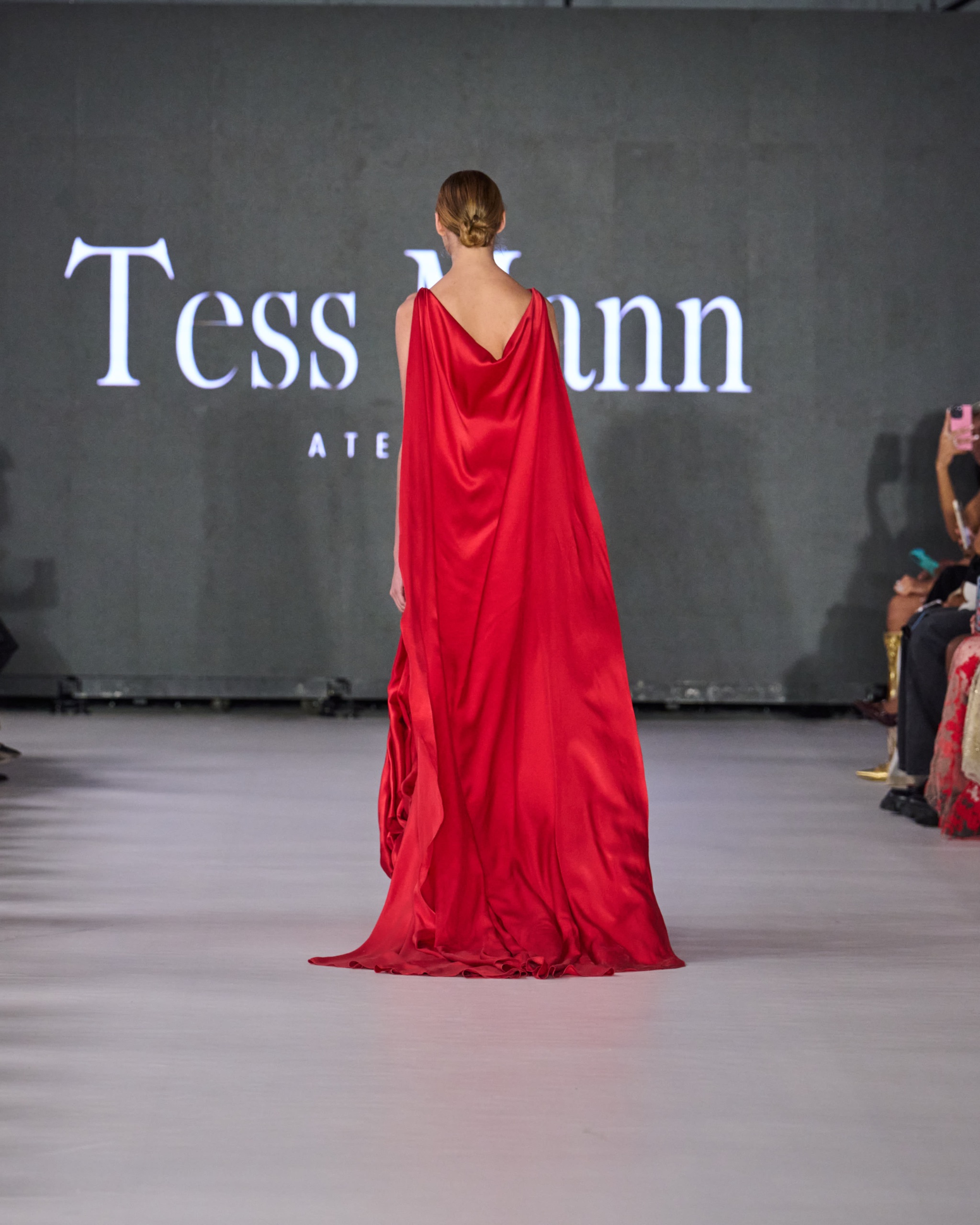 A model walking the runway wearing a long red dress.