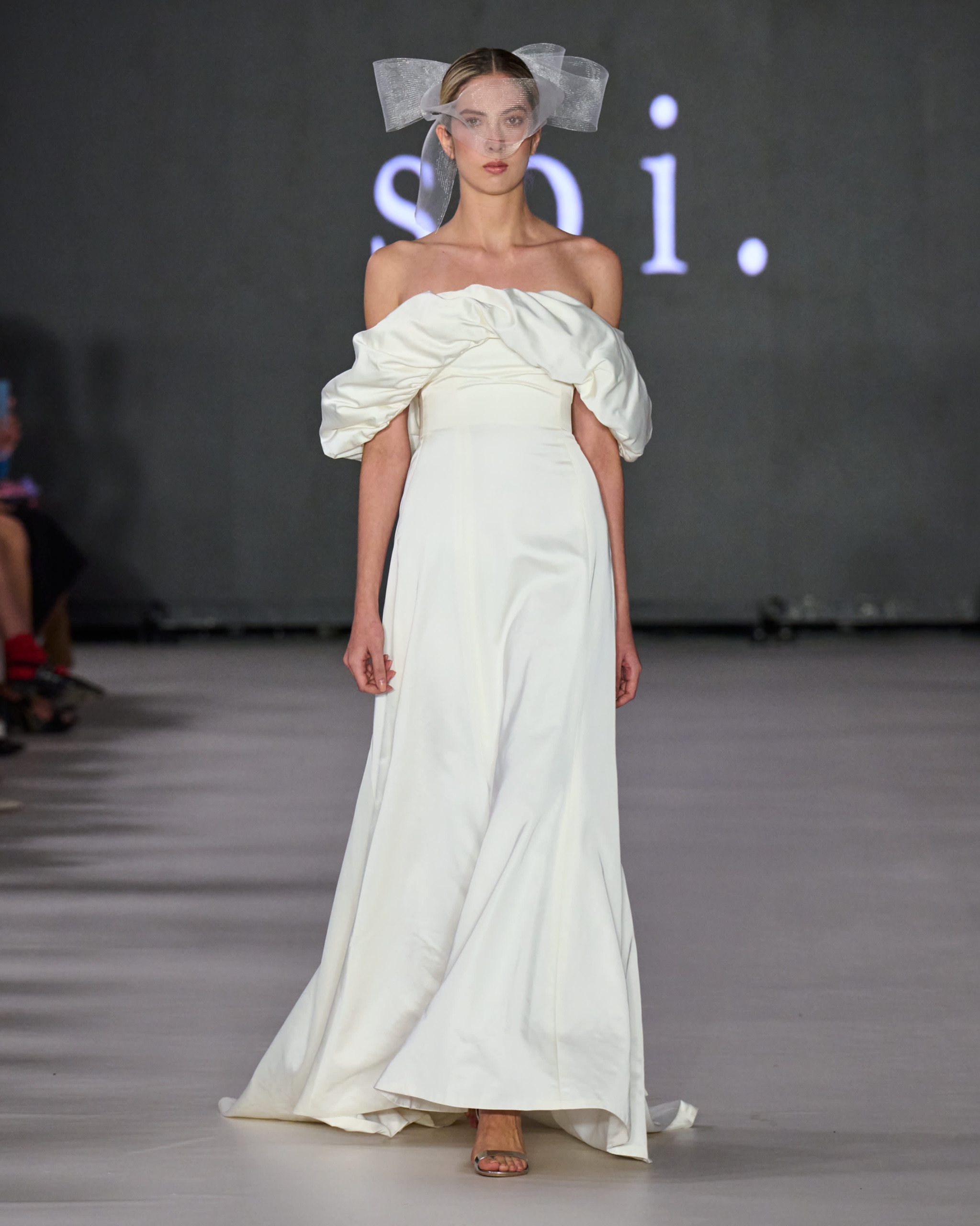 A model walking the runway wearing a long white dress.