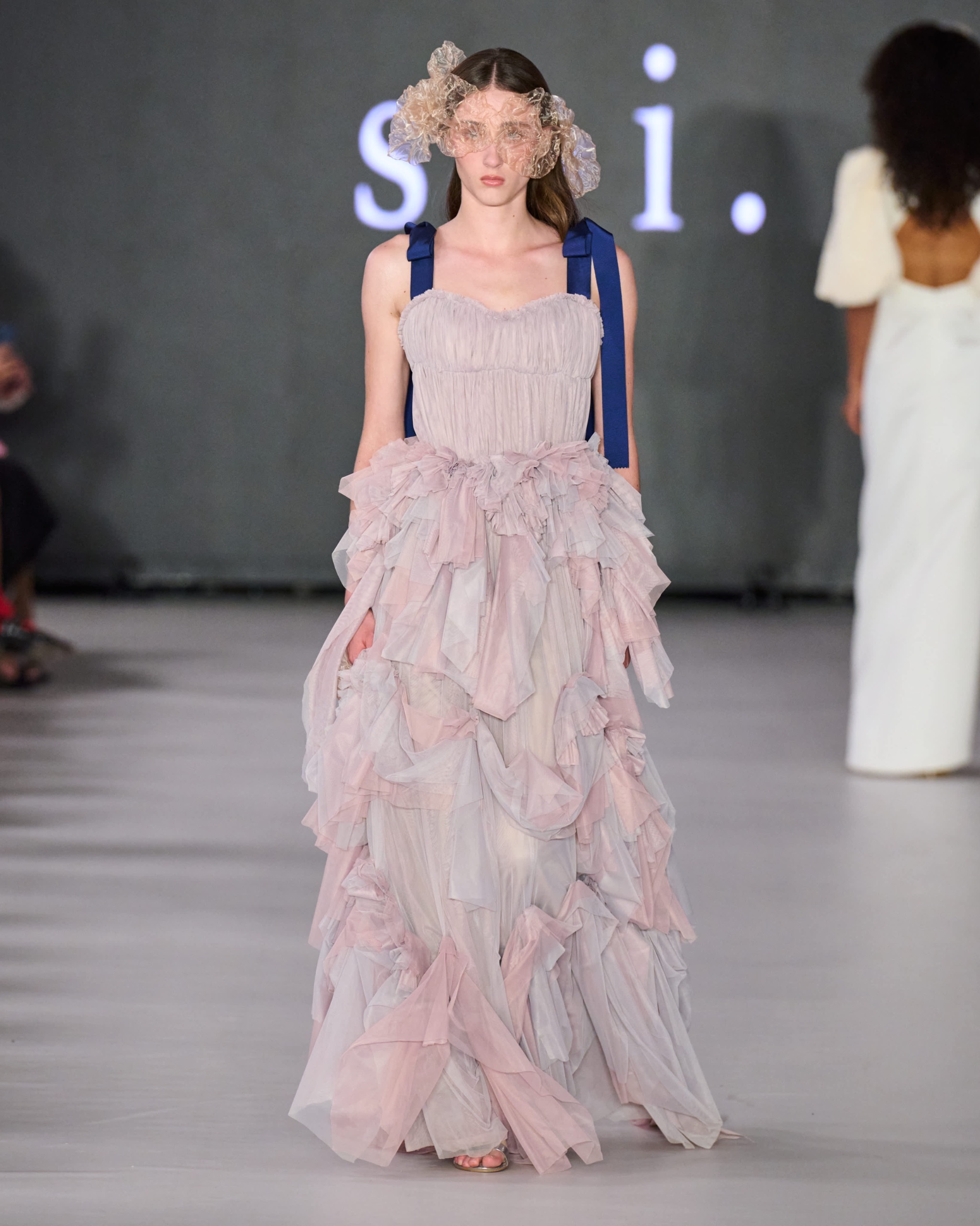 A model walking the runway wearing a lavender dress.