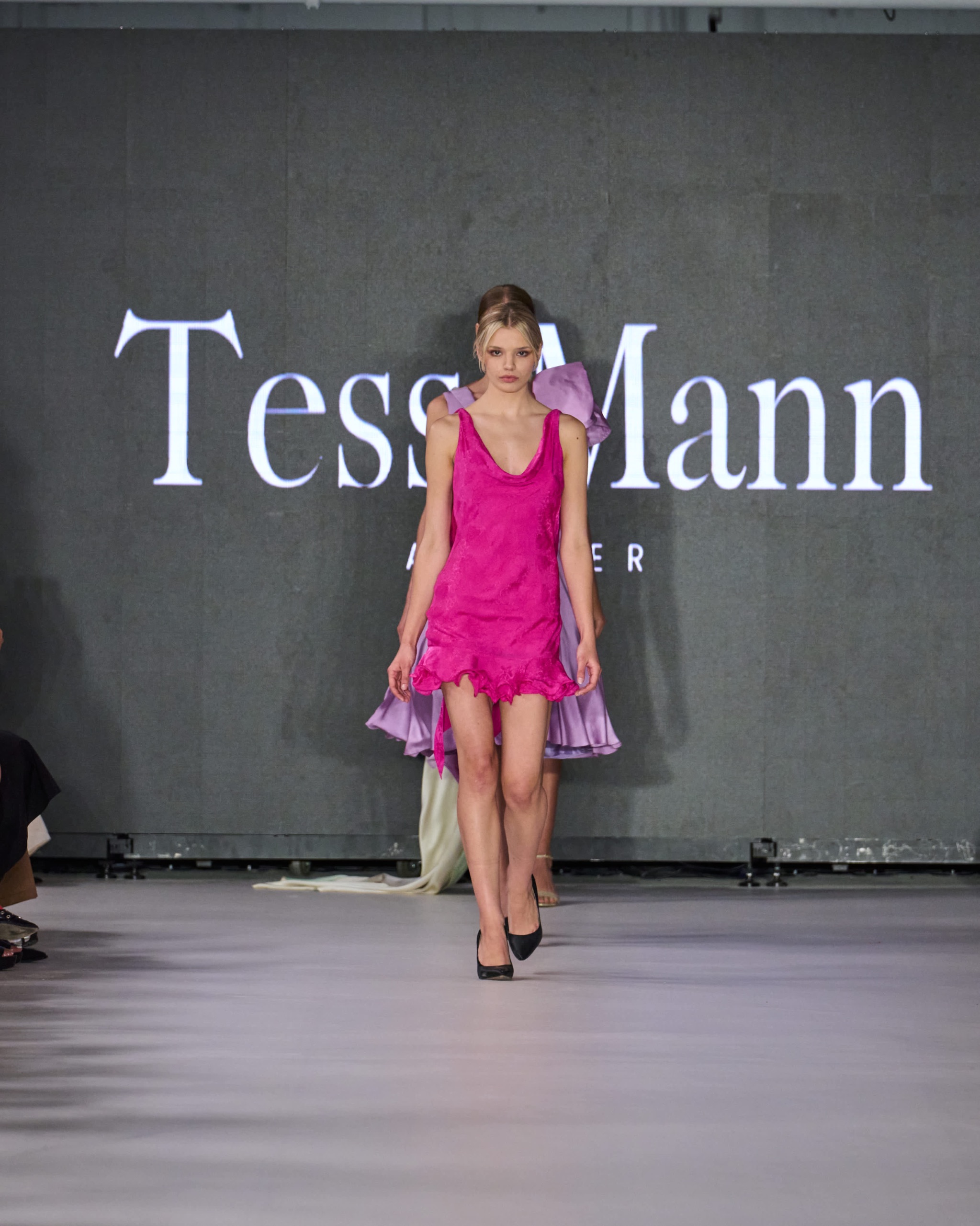 A model walking the runway wearing a pink dress.